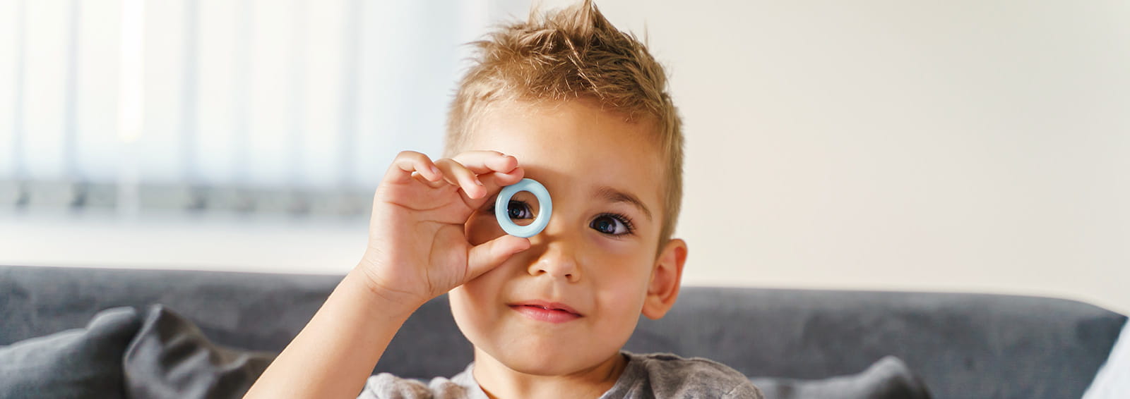 boy with holding blue ring to eye