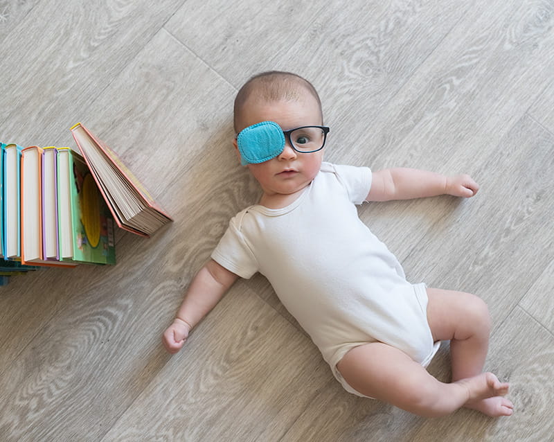 infant with glasses and eye patch